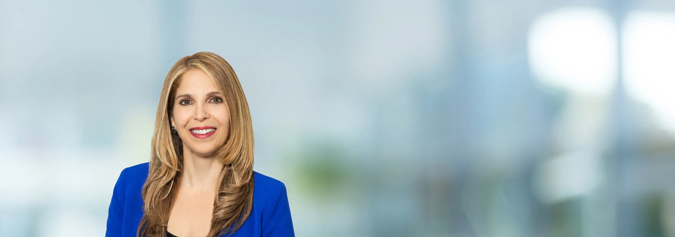 A photo of attorney Claudia Mourad against a softly blurred office background