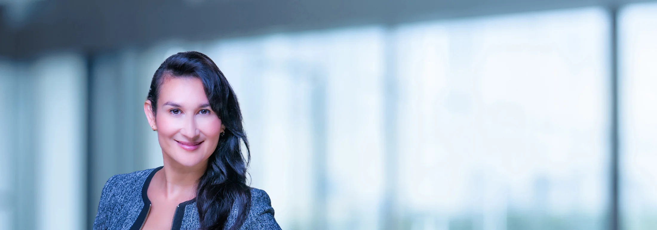 A photo of attorney, Elizabeth Del Cid, against a softly blurred office background
