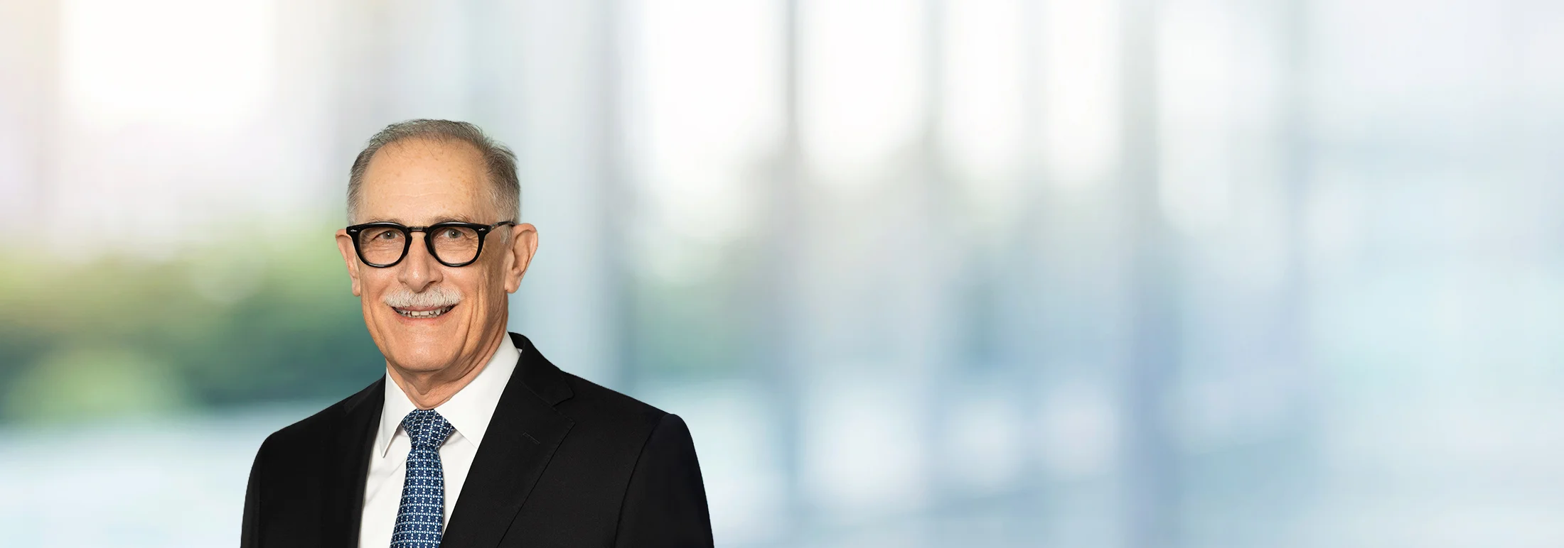A photo of attorney Dennis Kasper against a softly blurred office background
