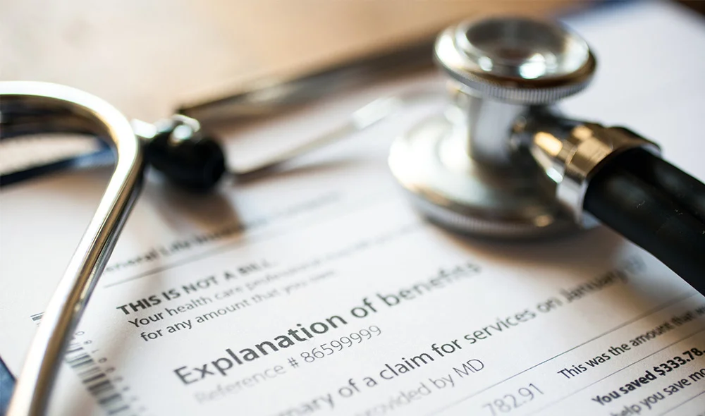 Close-up of legal documents on a desk, partially visible beneath a pair of metal-framed eyeglasses and a silver pen. The visible paper includes printed text in a formal layout, with a bold heading that appears related to a contract or agreement.