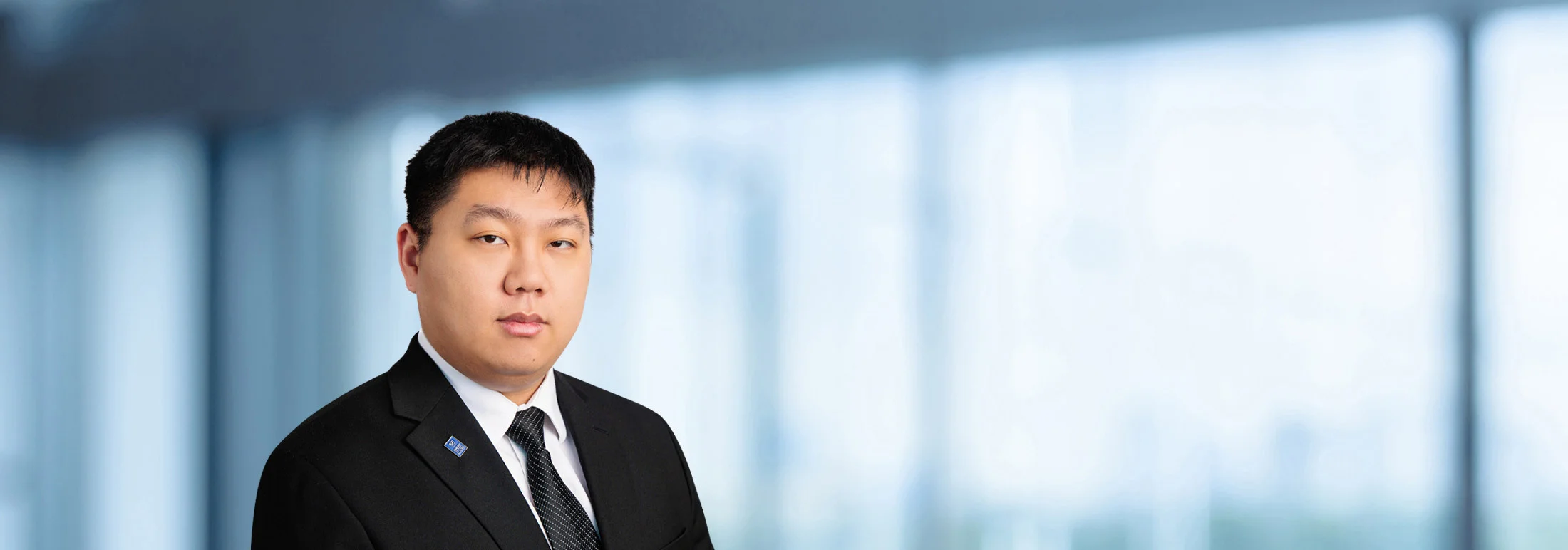 A photo of attorney, Daniel Wang, against a softly blurred office background.