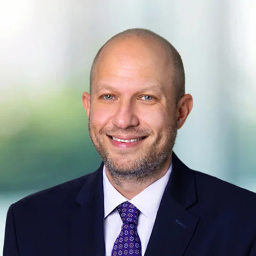 A photo of attorney, Andrew Schneiderman, against a softly blurred office background.